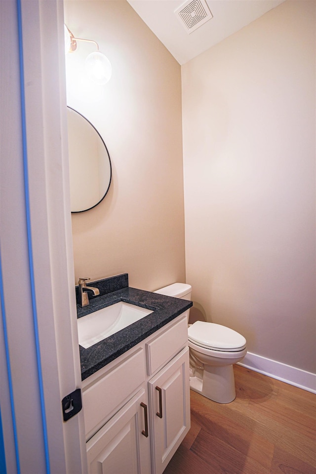 bathroom with hardwood / wood-style floors, vanity, and toilet