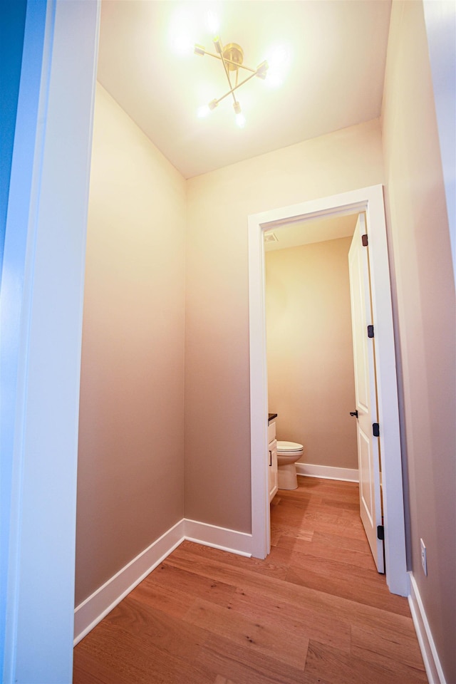 bathroom with hardwood / wood-style flooring, toilet, and a chandelier