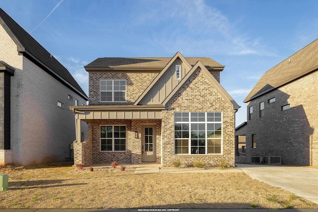 craftsman house featuring central air condition unit, a shingled roof, board and batten siding, and brick siding