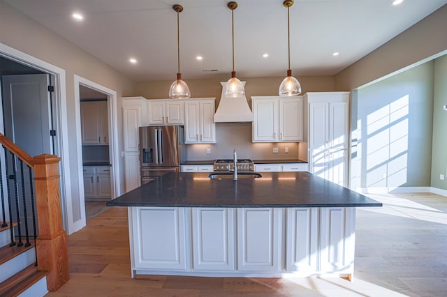 kitchen featuring white cabinets, stainless steel refrigerator with ice dispenser, hanging light fixtures, and a large island