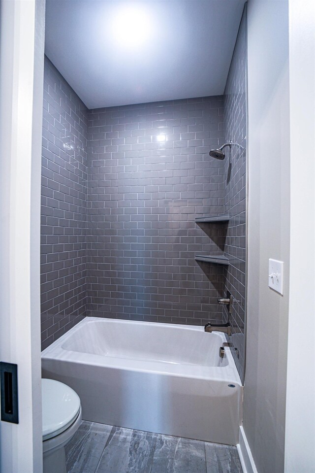 bathroom featuring toilet and tiled shower / bath