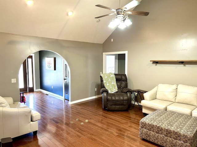 living room featuring arched walkways, ceiling fan, wood finished floors, and baseboards