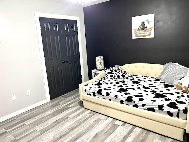 bedroom with a closet, baseboards, and wood finished floors