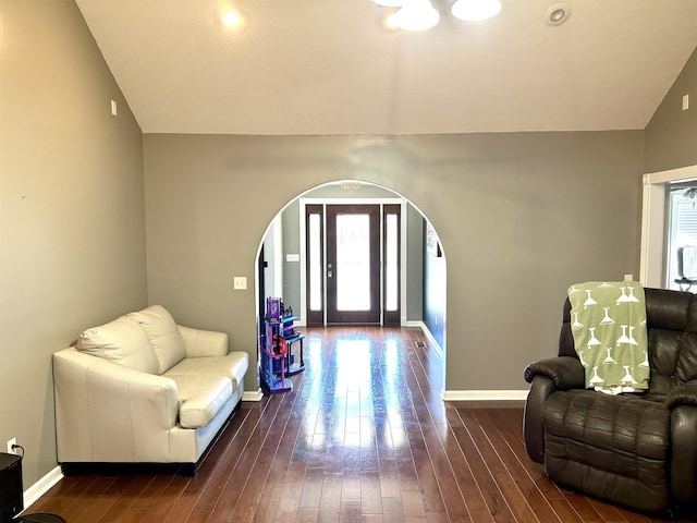 entrance foyer with lofted ceiling, arched walkways, dark wood-style floors, and baseboards