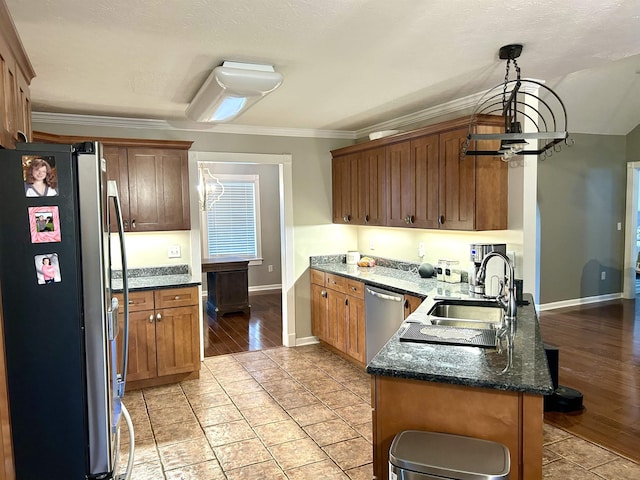 kitchen with appliances with stainless steel finishes, ornamental molding, a peninsula, a notable chandelier, and a sink