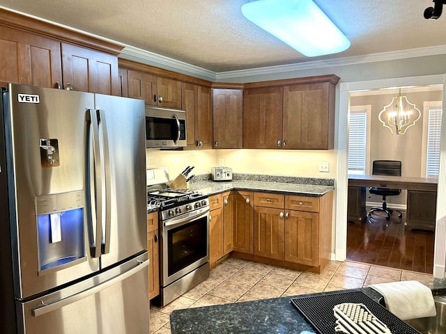 kitchen featuring a textured ceiling, stainless steel appliances, ornamental molding, and dark stone counters