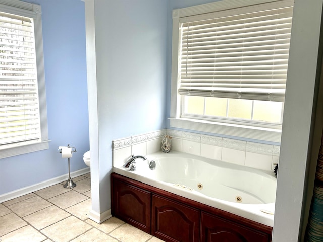 bathroom with a jetted tub, toilet, and baseboards