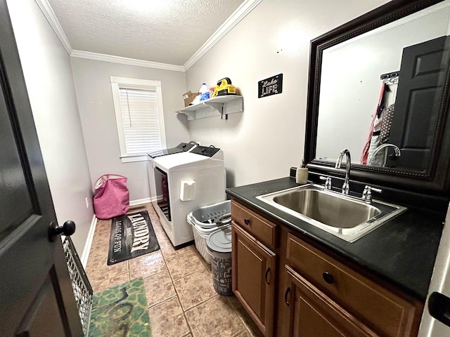 washroom with cabinet space, ornamental molding, washing machine and clothes dryer, a textured ceiling, and a sink