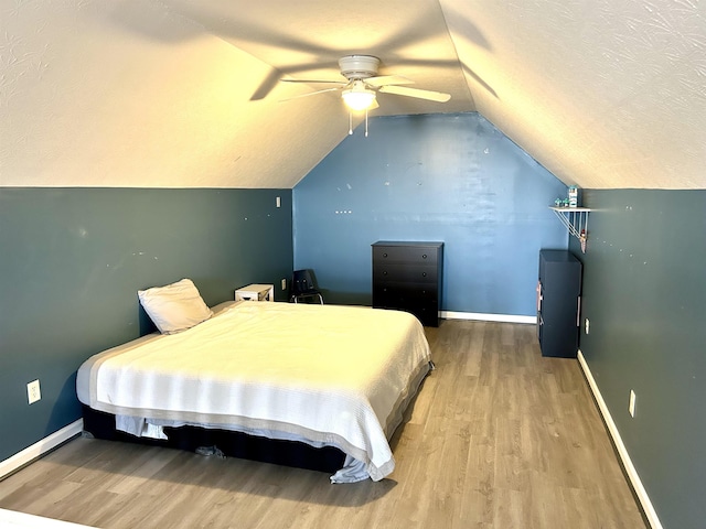 bedroom featuring a textured ceiling, vaulted ceiling, wood finished floors, and baseboards