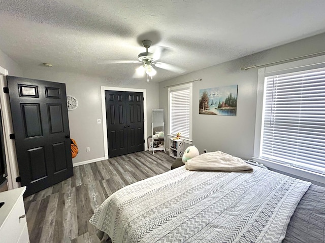 bedroom with a textured ceiling, wood finished floors, a ceiling fan, and baseboards