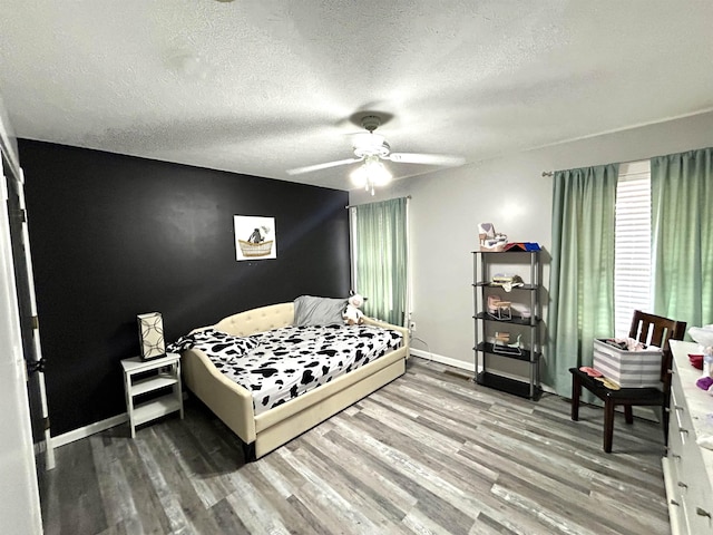 bedroom featuring a textured ceiling, wood finished floors, a ceiling fan, and baseboards