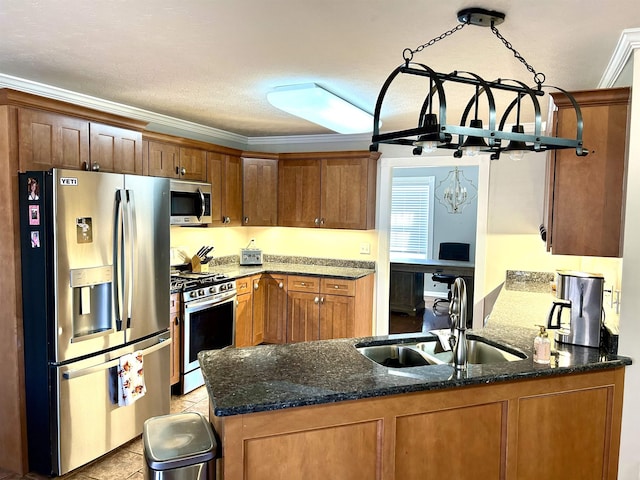 kitchen with appliances with stainless steel finishes, ornamental molding, a sink, dark stone counters, and a peninsula