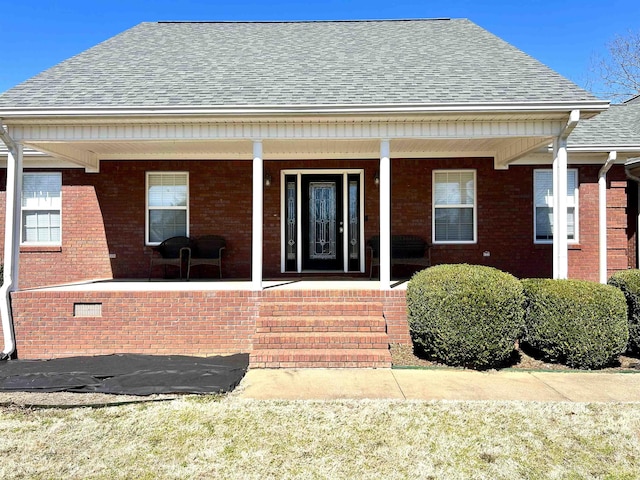 view of front of home with crawl space, a shingled roof, a porch, and brick siding