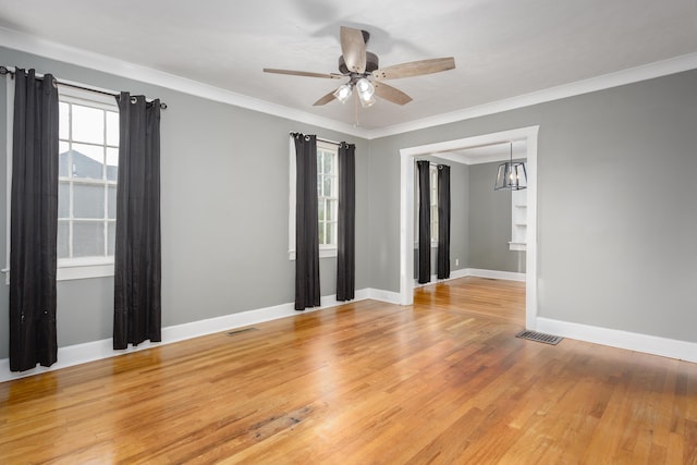 empty room featuring light hardwood / wood-style flooring, ceiling fan with notable chandelier, and ornamental molding