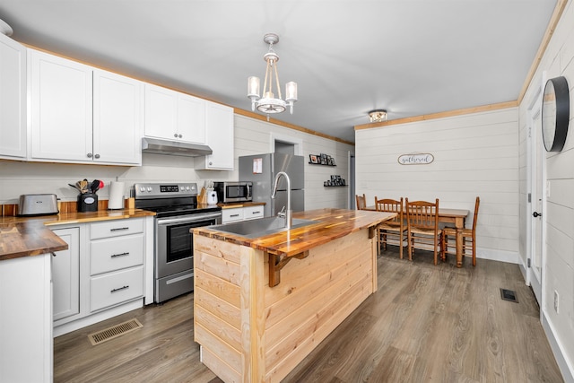 kitchen featuring white cabinets, appliances with stainless steel finishes, butcher block countertops, and decorative light fixtures