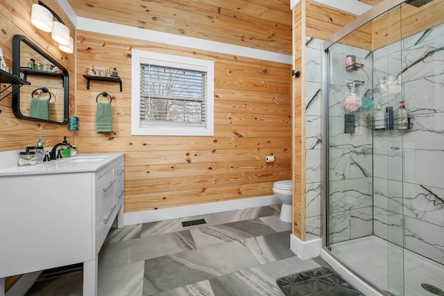 bathroom featuring vanity, toilet, a shower with shower door, and wooden walls