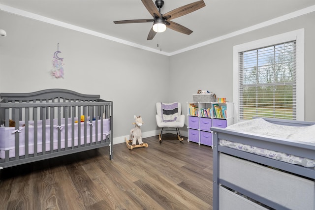 bedroom featuring ceiling fan, dark hardwood / wood-style flooring, a crib, and ornamental molding