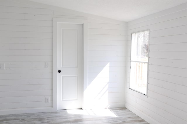  - spare room featuring wood walls and light wood-style flooring