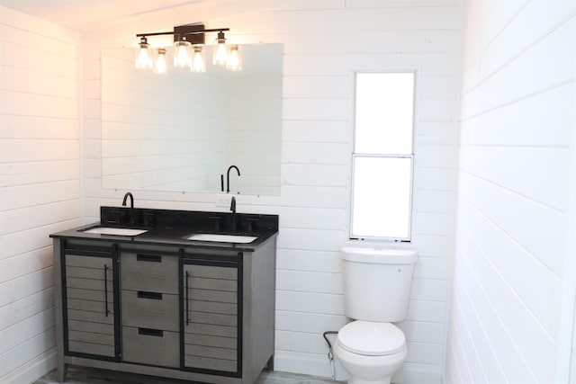  - bathroom featuring toilet, double vanity, and wooden walls