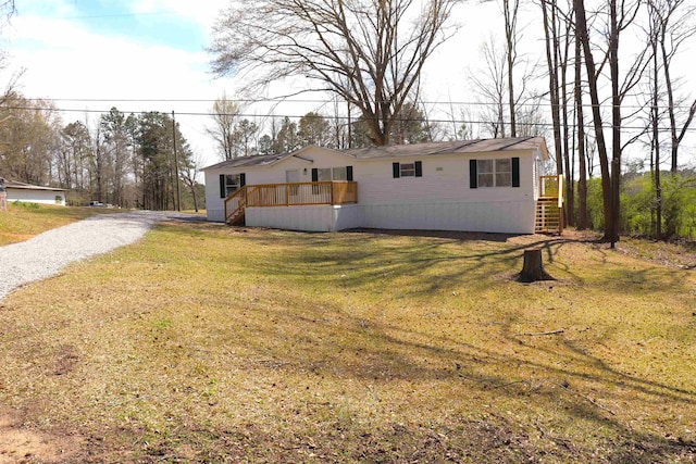  - view of front facade with a front yard, a wooden deck, stairway, and driveway