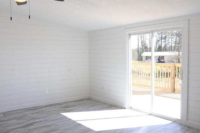  - empty room featuring a textured ceiling, light wood finished floors, a ceiling fan, and vaulted ceiling