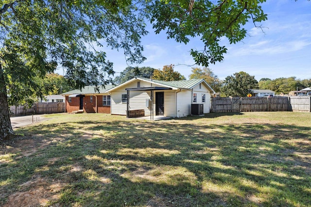 rear view of property featuring central AC unit and a yard