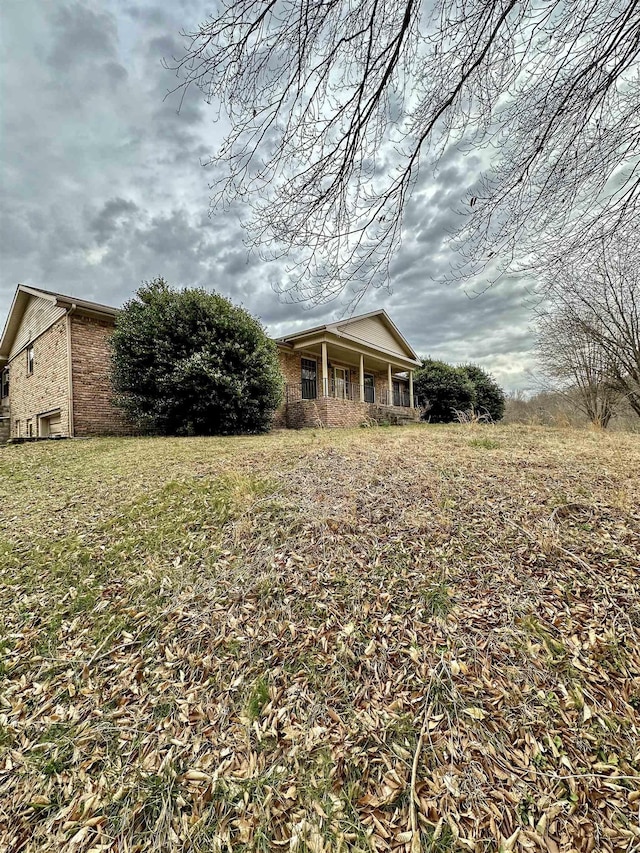 exterior space featuring a front yard, covered porch, and brick siding