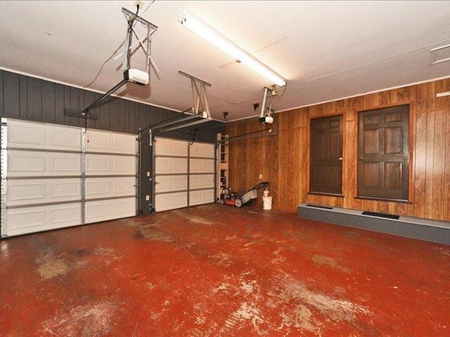 garage featuring a garage door opener and wooden walls