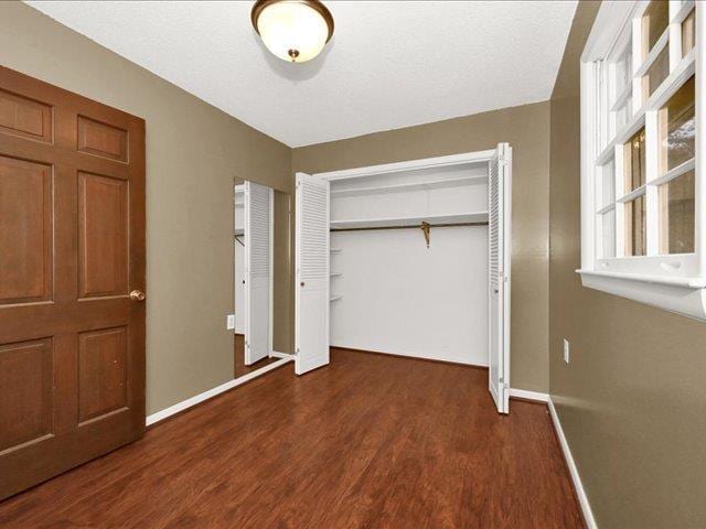 unfurnished bedroom with dark hardwood / wood-style flooring and a closet