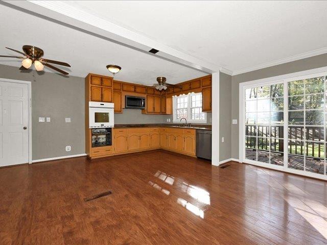 kitchen with sink, dark hardwood / wood-style flooring, ornamental molding, and stainless steel appliances