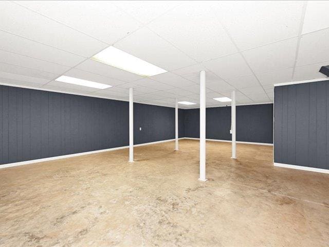 basement featuring a paneled ceiling and wooden walls