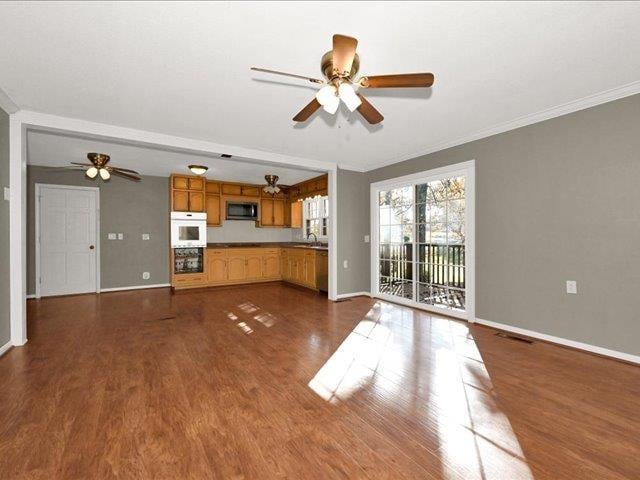 unfurnished living room with dark hardwood / wood-style flooring and ornamental molding