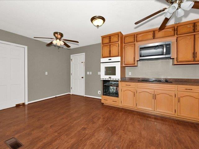 kitchen with dark hardwood / wood-style floors, white double oven, and black cooktop