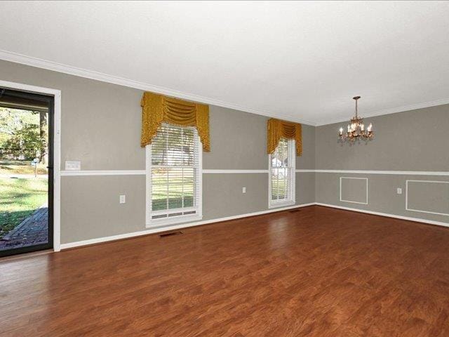 spare room with dark hardwood / wood-style flooring, plenty of natural light, and a notable chandelier