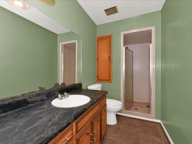 bathroom featuring a shower with door, vanity, and toilet