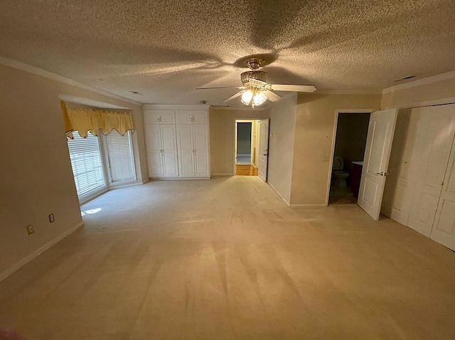 interior space with crown molding, a textured ceiling, light colored carpet, a ceiling fan, and baseboards