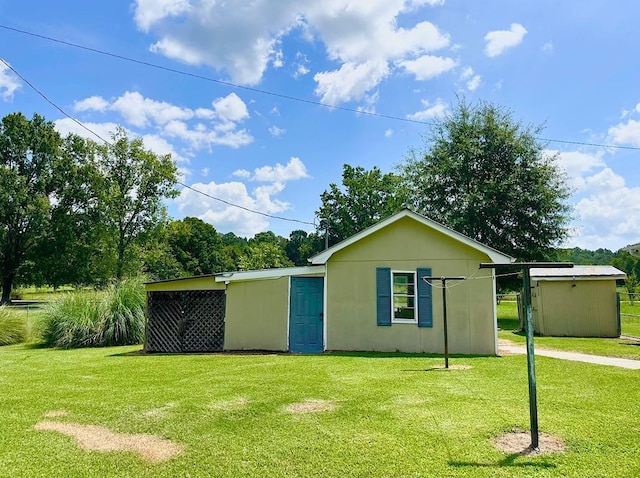 rear view of house featuring a yard, stucco siding, and an outbuilding