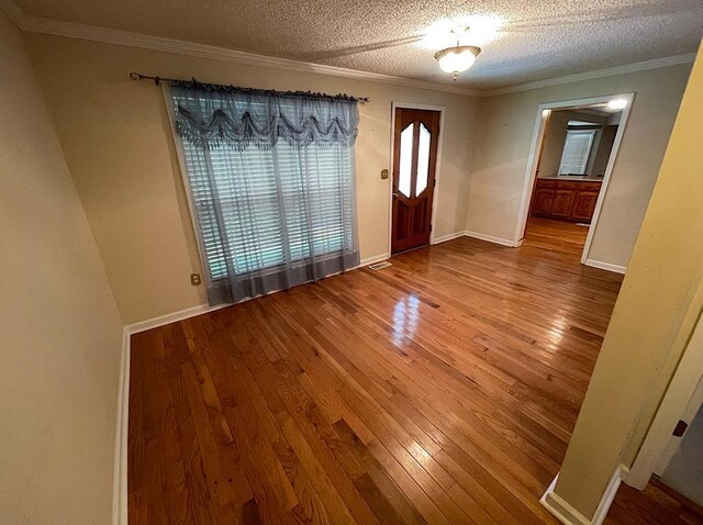 entryway with crown molding, a textured ceiling, and hardwood / wood-style flooring