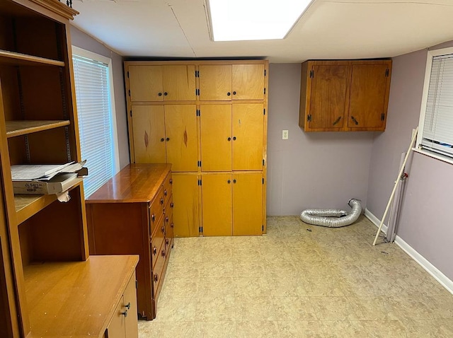 interior space with baseboards, light floors, and cabinet space