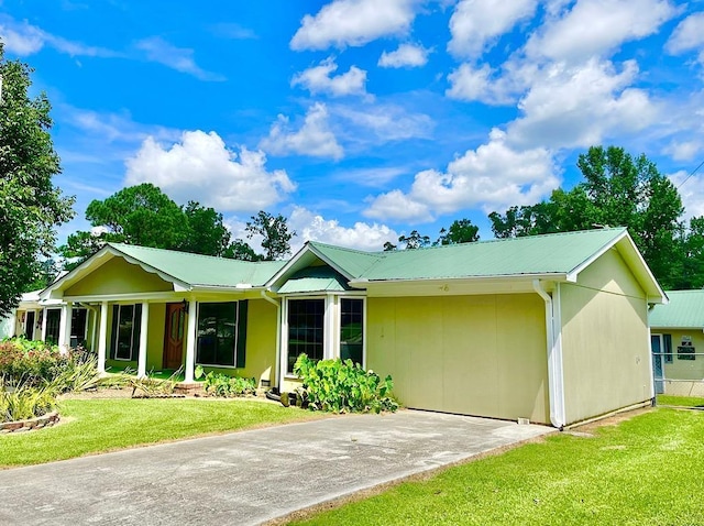 ranch-style house with a front yard, metal roof, driveway, and fence