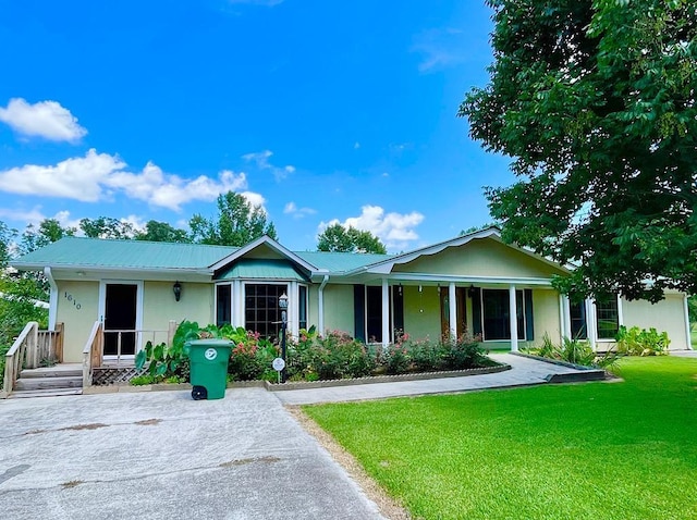 ranch-style home featuring a porch, metal roof, and a front lawn