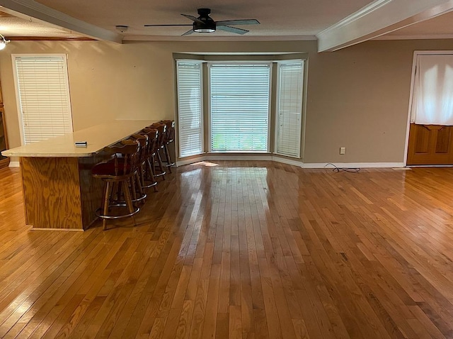 interior space with crown molding, a dry bar, wood-type flooring, and a ceiling fan