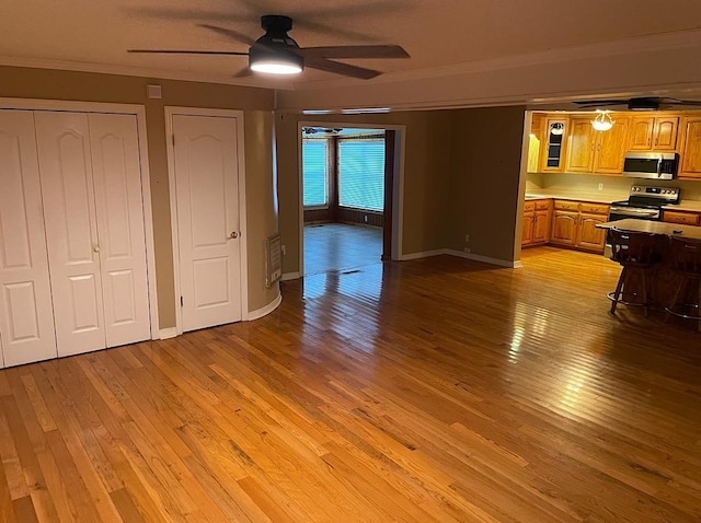unfurnished living room featuring crown molding, baseboards, a ceiling fan, and light wood-style floors