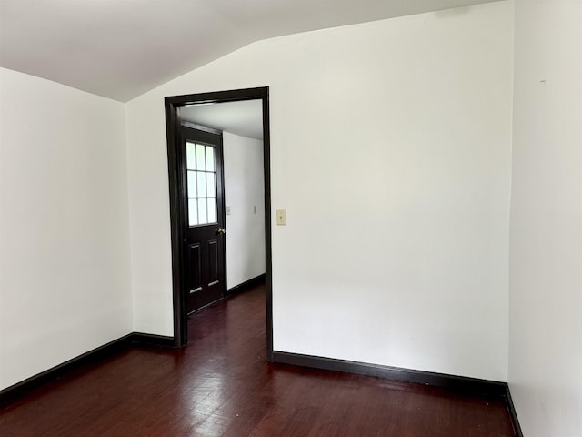 empty room with baseboards, dark wood-style floors, and vaulted ceiling