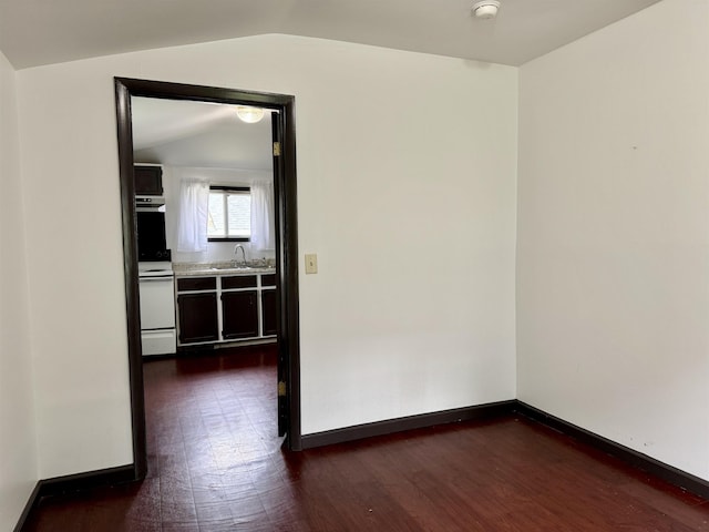 spare room with baseboards, a sink, dark wood-style flooring, and vaulted ceiling