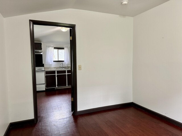  - spare room with baseboards, a sink, dark wood-style flooring, and vaulted ceiling