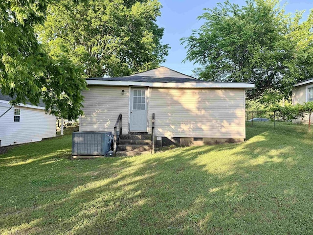 rear view of property featuring fence, central air condition unit, a yard, and entry steps