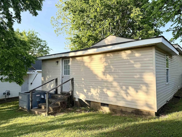 view of side of home featuring central air condition unit, a lawn, and crawl space