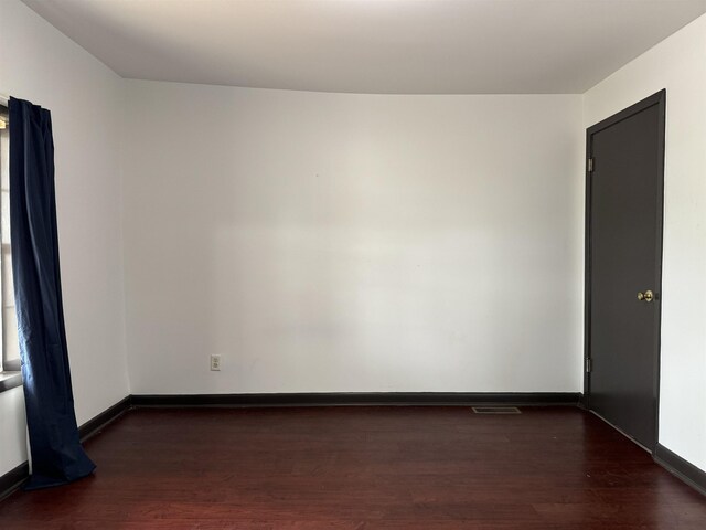 - unfurnished room featuring baseboards, visible vents, and wood finished floors