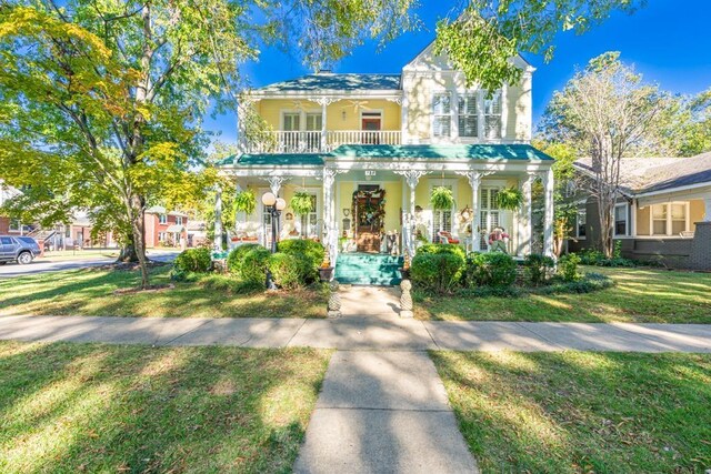 view of front of home with covered porch, a balcony, and a front yard